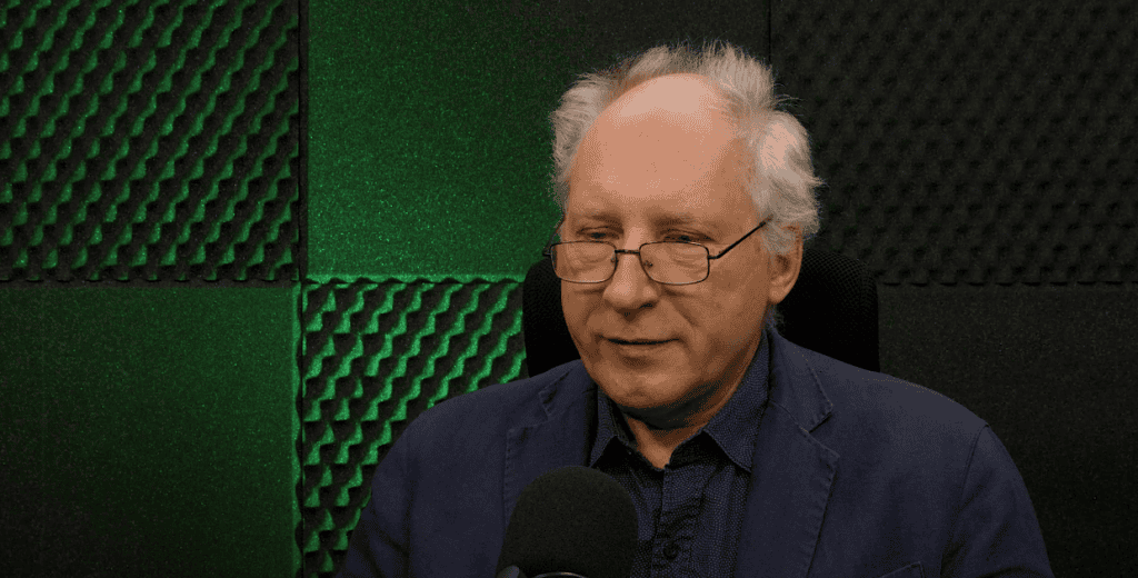 Sędzia szczęśliwy w studio nagraniowym, mężczyzna rozmawia z mikrofonem, dźwiękoszczelne panele, profesjonalny sprzęt studyjny, skupiony i spokojny nastrój, idealne do nagrań lub podcastów.