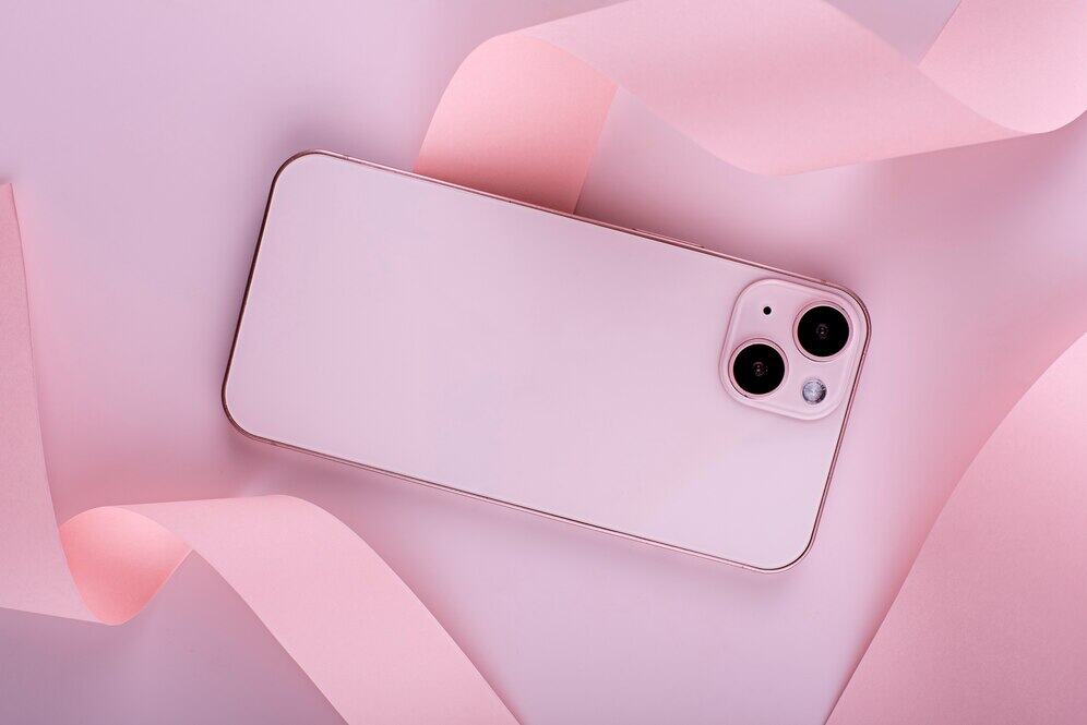 Nowoczesny różowy smartfon na pastelowym tle z delikatną kokardą, idealny na prezent, do codziennego użytku i dla miłośników nowych technologii.
