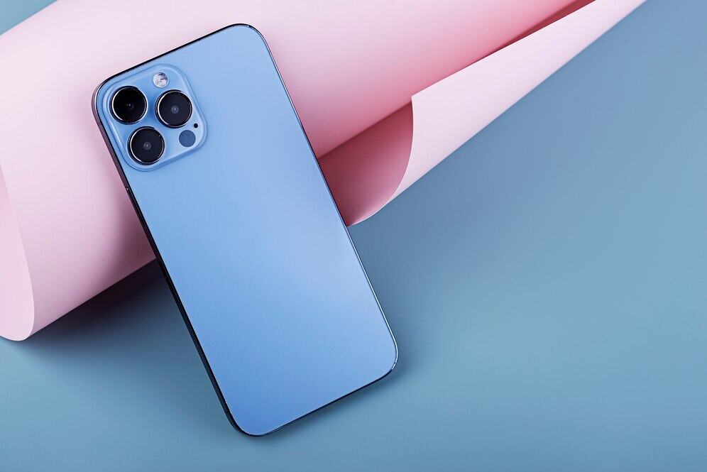 Modny smartfon w niebieskim kolorze na pastelowym tle, idealny do codziennego użytku i fotografowania. Nowoczesny design i wysokiej jakości aparat dla użytkowników ceniących styl i funkcjonalność.