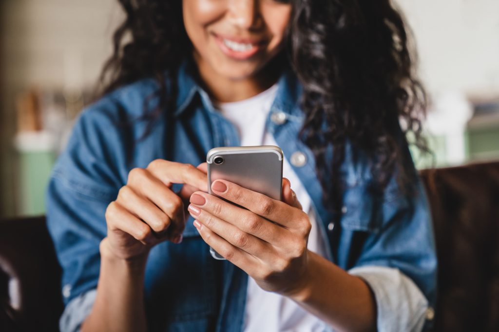 Młoda kobieta uśmiecha się do telefonu